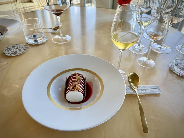 Croccante all’amarena, che si ispira al celeberrimo gelato e lo ricorda perfettamente. Soufflè di yogurt ghiacciato al momento, servito con vino di visciole, noccioline pralinate, zuppetta di amarene e karkadè. Si beve in pairing a un Estratto di ananas flambato e menta fresca