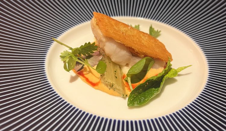 Triglia di scoglio in una finissima crosta di legumi, con salsa agrodolce ai peperoni di Carmagnola, sedano rapa e un cardo sotto. Pesce, verdure, legumi in un intreccio saggio e inedito tra nord e sud