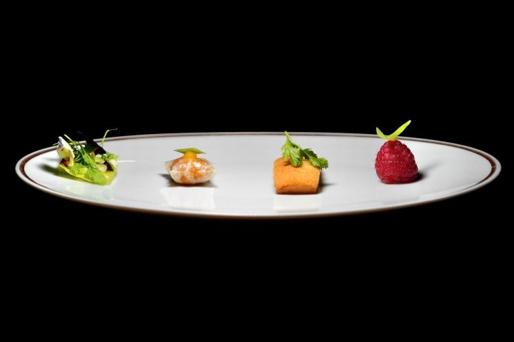 Appetizer. Da sinistra Insalatina di recupero con burro di alici e gel di agrumi, Barbagiuan con zucca, arancia ed erbe aromatiche, Financier alla mandorla, Lampone con burro di harissa. A lato un Gazpacho di cachi, arancio e tabasco