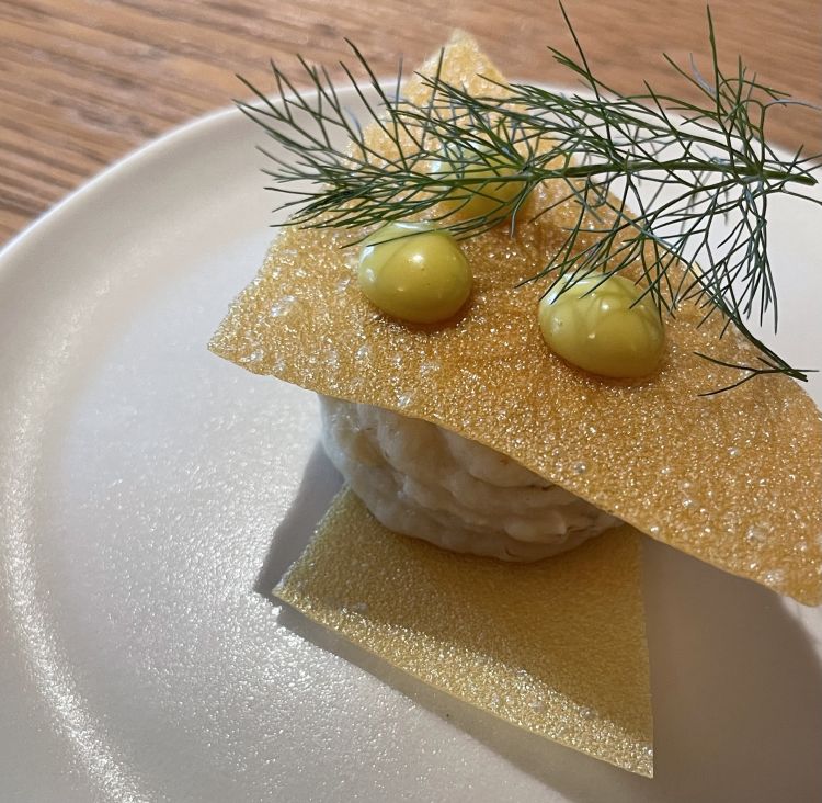 Nessuna carrellata di amuse-bouche, ma un solo e unico benvenuto; l'essenziale si manifesta anche in questo: due sfoglie di patata, veli croccanti, e delicato baccalà mantecato