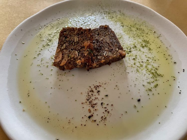 Primo benvenuto dalla cucina: Pane ai grani senza glutine, burro caramellato, polvere di Erba Luigia
Un inizio di golosità essenziale, che anticipa lo spirito della cucina della Trattoria