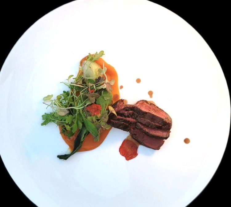 Manzo Marango alla fiamma, patata dolce ed erbe amare
Nell’ultimo piatto ritroviamo la carne di manzo Marango (un incrocio tra la Maremmana e la Frisona con il Black Angus). In questo caso ci viene proposto il filetto scottato alla fiamma, cottura al sangue, e viene accompagnato da una crema di patata dolce ed erbe amare
